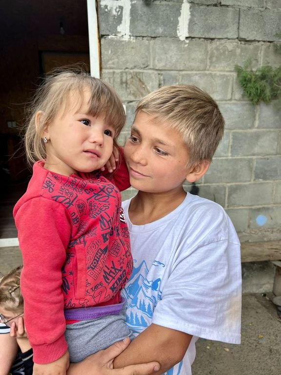 Ein älterer Junge trägt ein Kleinkind auf dem Arm